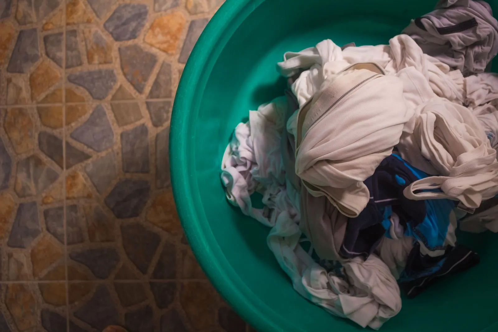 Panier de linge propre trié par couleurs dans une buanderie rangée, paniers empilés et étagères.