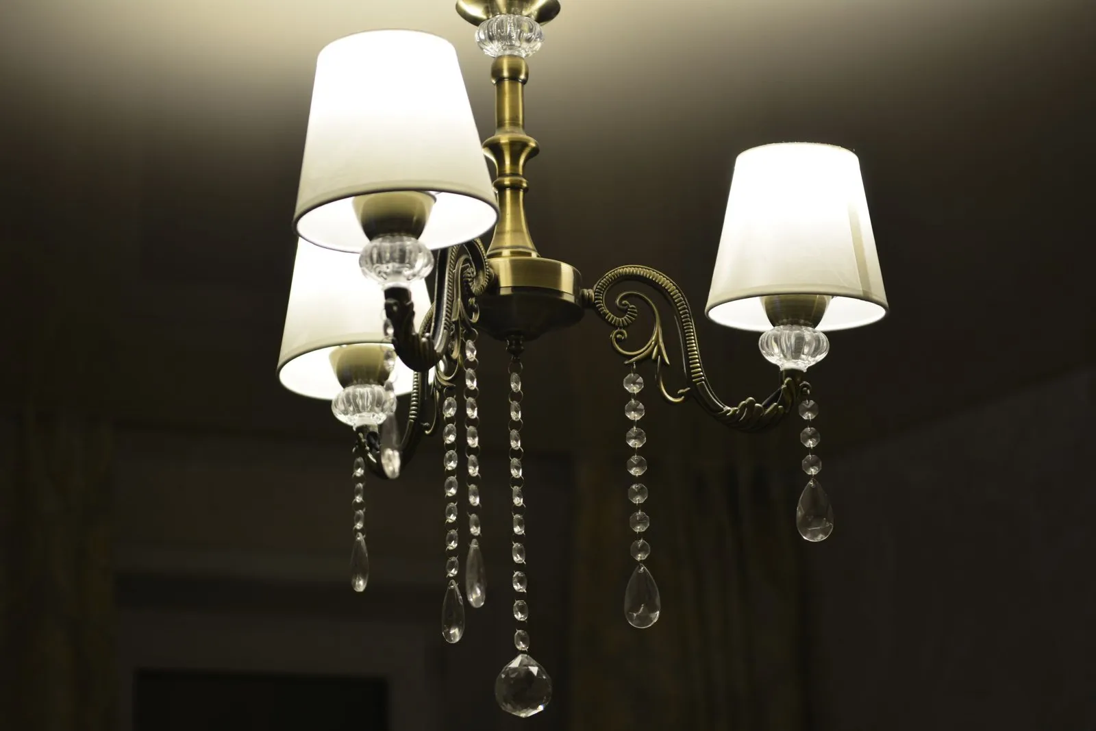 Lustre cristal de Bohême à pampilles, suspendu dans un salon classique baigné de lumière chaude